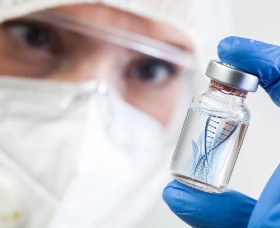A researcher looking at RNA in a glass vial.