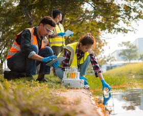Three scientists collecting water samples from a river.