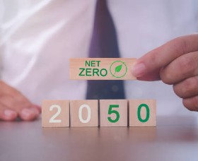 A businessman with wooden blocks in front of him spelling 'Net Zero 2050'
